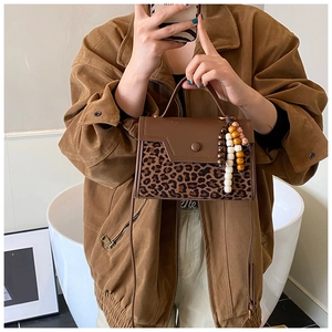 Mirror selfie showing a vintage leopard print handbag with brown leather flap and bead tassel