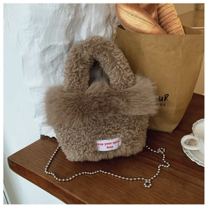 Detail of plush brown teddy fleece crossbody bag with metal chain and textile label