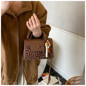 Detail of leopard print and brown leather handbag with bohemian wooden bead charm