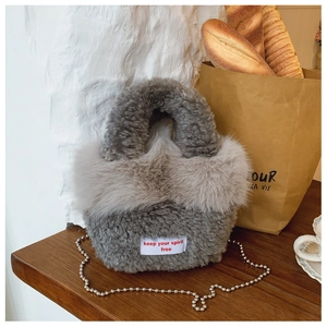 Detail of grey plush faux fur shoulder bag with silver bead chain and white woven label