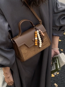 Vintage brown leather crossbody bag with beaded charm and geometric flap design