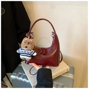 Detail of burgundy hobo bag in glossy leather featuring a cute plush bear charm