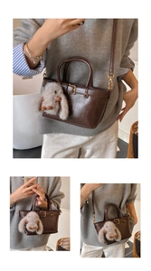 Détail du sac à main en similicuir marron foncé avec boucles dorées et breloque lapin
