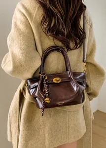 Detail of deep brown leather bucket bag with gold twist lock and brand logo shown on model