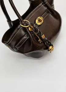 Macro shot of brown vintage leather bucket bag featuring white stitching and gold twist lock