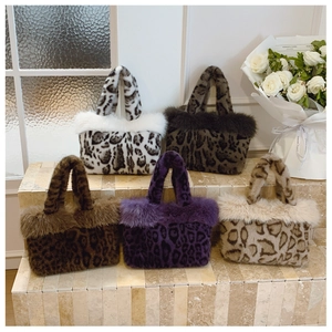 Detail view of five colors of plush leopard print tote bags on decorative stone steps