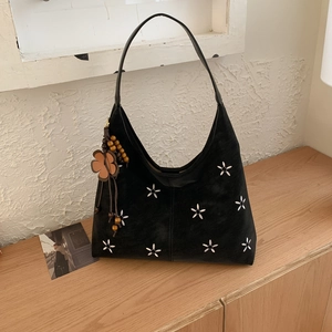 Detail van zwarte suède hobo tas met witte geborduurde bloemen en houten kralen hanger decoratie
