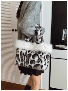 Detail of leopard print faux fur tote bag with plush white trim held by a model