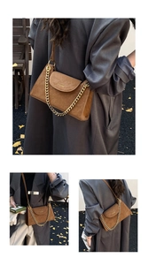 Detail of a brown faux leather shoulder bag with a stylish gold chain and flap closure