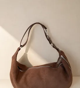 Dettaglio della borsa hobo in camoscio marrone con cerniera argentata e ganci in metallo