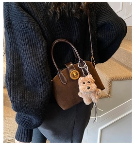 Detailansicht dunkelbraune mattierte Wildledertasche mit Goldverschluss und Bärenanhänger