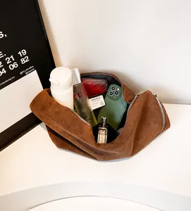 Dettaglio degli interni spaziosi della borsa in pelle scamosciata marrone scuro con oggetti