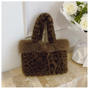Close-up of leopard print faux fur tote bag with plush trim on a marble surface