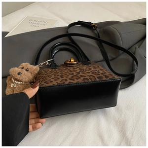 Detail der Handtasche mit Leopardenmuster, goldenem Drehverschluss und braunem Plüsch-Anhänger
