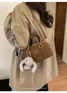 Detail of brown suede bowling bag with cute rabbit pendant and embossed brand lettering