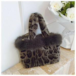 Detailed view of leopard print plush tote bag with faux fur trim on stone surface