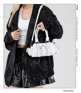 Close-up of white Y2K style handbag with punk metal buckles and rivets shown on a model