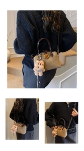 Detail einer khakifarbenen matten Handtasche mit braunen Griffen und Plüschbär-Anhänger