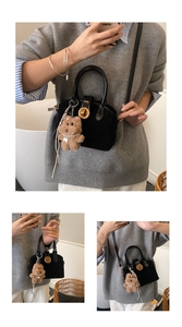 Detailansicht der schwarzen matten Mini-Handtasche mit Goldschloss und Bärenanhänger