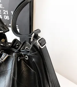 Détail de la boucle argentée ajustable et texture en cuir matelassé sur le sac seau noir