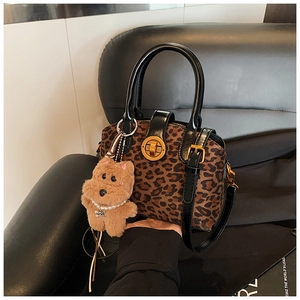 Detail der Handtasche mit Leopardenmuster, Goldschnalle und süßem Welpenanhänger mit Perlen