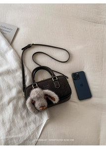 Detail view of a retro dark brown suede bowling bag with a cute plush rabbit charm