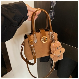 Detail der vintage matten braunen Handtasche mit Golddrehschloss und Plüschtieranhänger