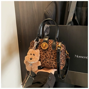 Detail der Vintage-Handtasche mit Leopardenmuster, Goldschloss und Plüschanhänger