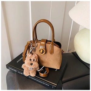 Detailansicht der Retro-Handtasche aus khakifarbenem Wildleder mit Welpen-Anhänger