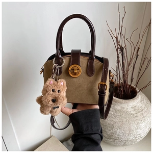 Detailansicht der Retro-Handtasche aus khakifarbenem Wildleder mit braunen Riemen und Schloss