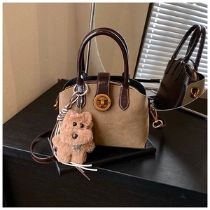 Details einer Vintage Khaki Handtasche mit Plüschwelpen-Anhänger und Metallverschluss