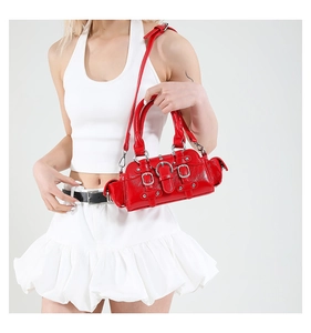 Close-up of a glossy red Y2K handbag with silver rivets and studs on a white background