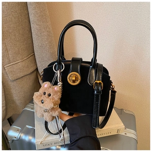 Details der schwarzen Vintage-Tasche mit Goldverschluss und Plüsch-Hundeanhänger