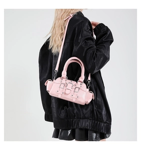 Detail of pink punk style cylinder bag with silver metal buckles and rivets worn by model
