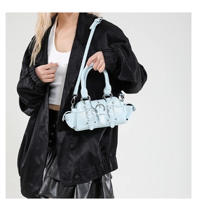 Detail of light blue patent leather handbag with silver buckles and strap accents