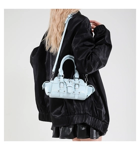 Detail of light blue glossy leather motorcycle bag featuring silver buckles and buckles