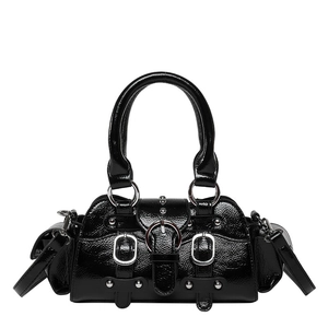 Close-up of black patent leather handbag featuring silver metal buckles and punk studs
