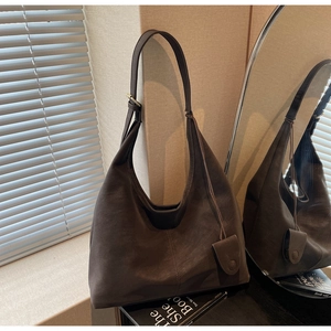 Macro detail of brown suede hobo bag featuring vertical stitching and adjustable buckle