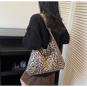 Detail of large capacity leopard print tote bag with wide shoulder strap worn by a model