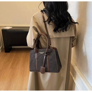 Detailansicht der grauen Vintage-Tragetasche mit Lederbesatz am Model im Trenchcoat