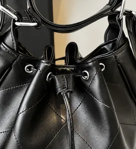 Vue détaillée du sac seau en cuir noir matelassé montrant le cordon de serrage et l'attache