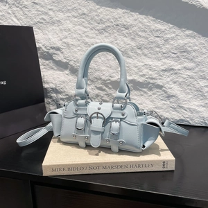 Fashionable light blue moto-style handbag with silver buckles and studs on an art book