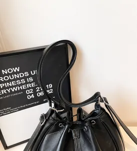 Détail d'un sac seau noir matelassé avec fermoir argenté et fermeture à cordon coulissant