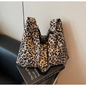 Close-up of leopard print shoulder bag with silver metal buckle on a black sofa