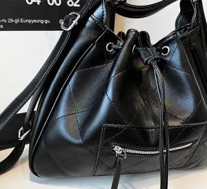 Détail d'un sac seau matelassé noir avec accessoires argentés et fermeture à cordon