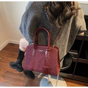 Detail der burgunderroten Vintage-Tasche mit matter Textur und Doppelgriff-Design