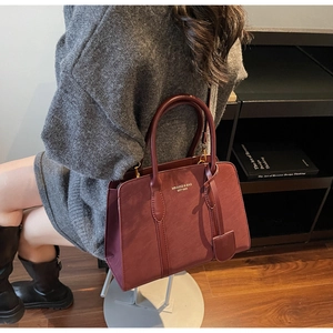 Detailansicht der weinroten Ledershoppingtasche mit eleganten Griffen und Markenlogo-Text
