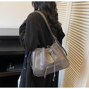 Détail du sac seau matelassé gris avec cordon de serrage porté par un mannequin
