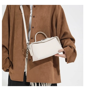 Detail showing the creamy beige crossbody box bag with handle and silver hardware zipper
