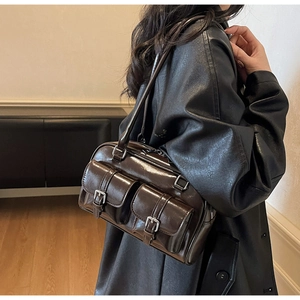 Detail of dark brown glossy bowling bag with two buckle front pockets on model